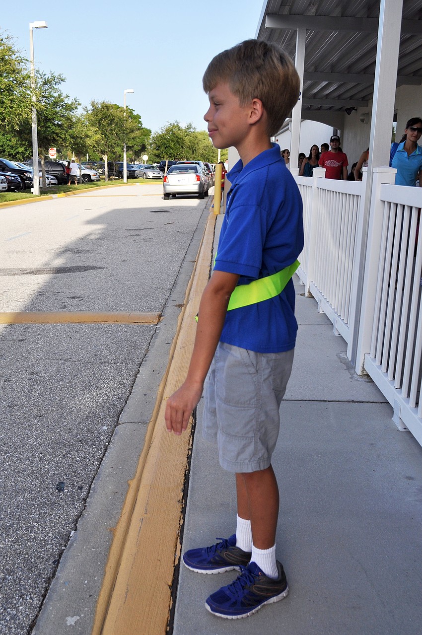Safety patroller Roan Lunte directs carpool traffic on the first day of school.
