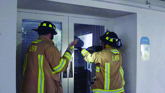 Lt. Jason Berzowski and firefighter/paramedic Bill Fortner attempt to enter a doorway Friday, at the vacant hotel.