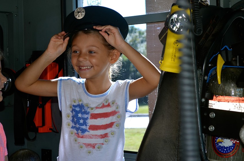 Katelyn Schneider tries on a hat she finds inside of a West Manatee firetruck.