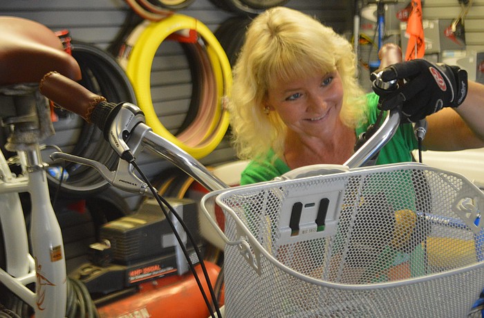 Lisa Nichols attaches a basket to a bicycle at the Backyard Bike Shop on Longboat Key. She has co-owned the shop with her husband, Charlie, since the late Ã¢â‚¬â„¢90s.