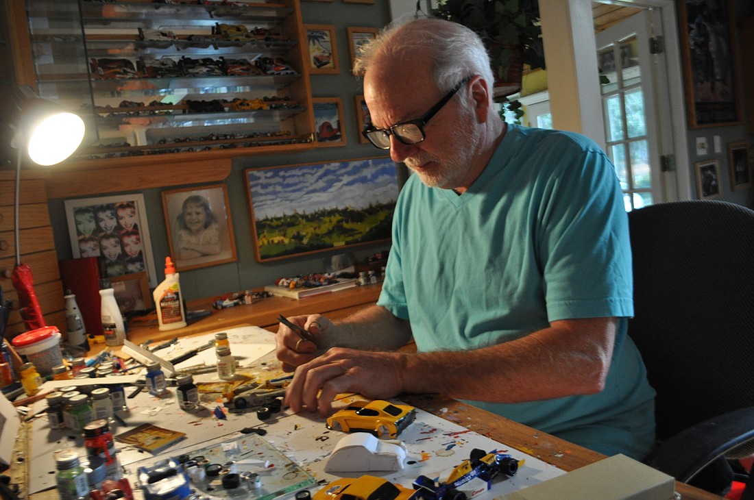 Pat Ringley, a cabinet maker and artist, works on a miniature race car made of paper at a desk in his East County home. Ringley has hundreds of his cars on display throughout his house. Photos by Amanda Sebastiano and Pam Eubanks