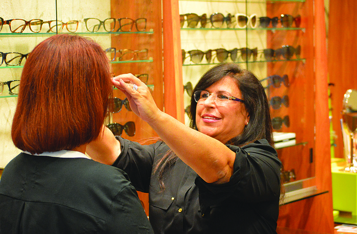 Yvonne Schloss, owner of Sunglass Express Optical, fits a customer with new glasses Monday, at her St. Armands Circle store. Schloss believes the mall will draw more potential shoppers to the area. Photo by Caleb Motsinger