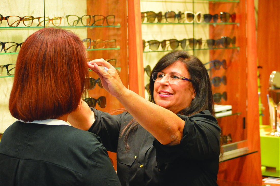 Yvonne Schloss, owner of Sunglass Express Optical, fits a customer with new glasses Monday, at her St. Armands Circle store. Schloss believes the mall will draw more potential shoppers to the area. Photo by Caleb Motsinger