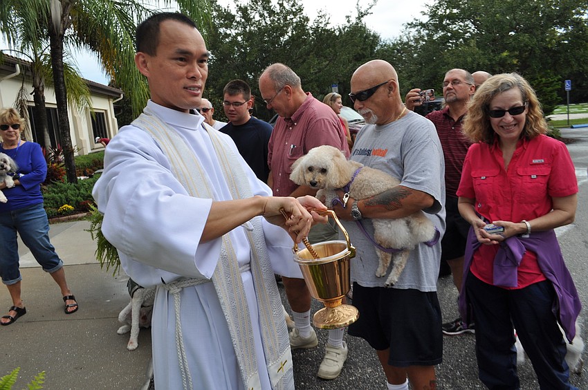 The Rev. John Nghia Hoang sprinkles the crowd of pets with holy water after saying a prayer.