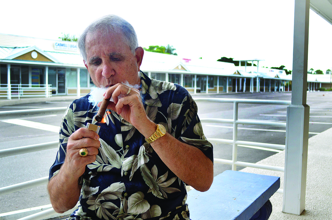 Dr. Giacomo "Jack" Guggino, lights up a Churchill style cigar at the location of his new cigar bar on Whitney Beach Plaza. He says even though it's a bit ironic, cigars are what paid his way through medical school. Photo by Caleb Motsinger