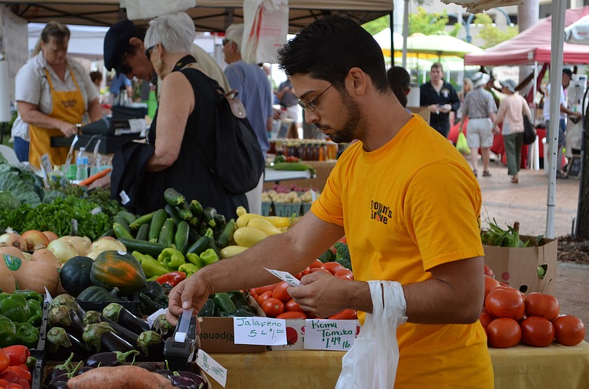drew Boeras of Brown Grove sets up the produce displays for the Wednesday Farmers Market at Five Points Park.