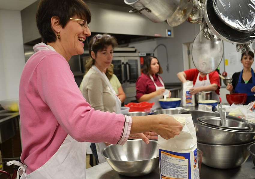 Sharon Kunkel adds flour to her mixing bowl to make challah bread.