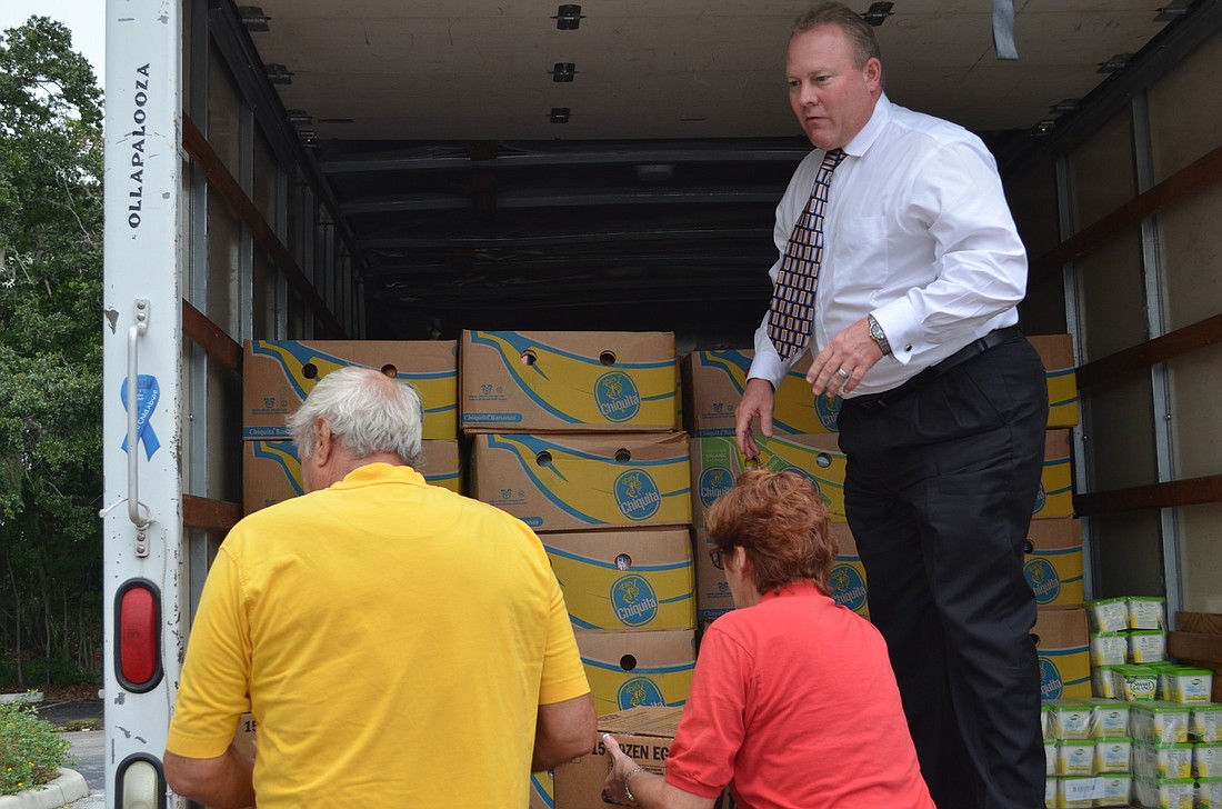 Child Protection Center Executive Director Doug Staley helps unload boxes of food donated by the Gulf Gate Rotary Club.