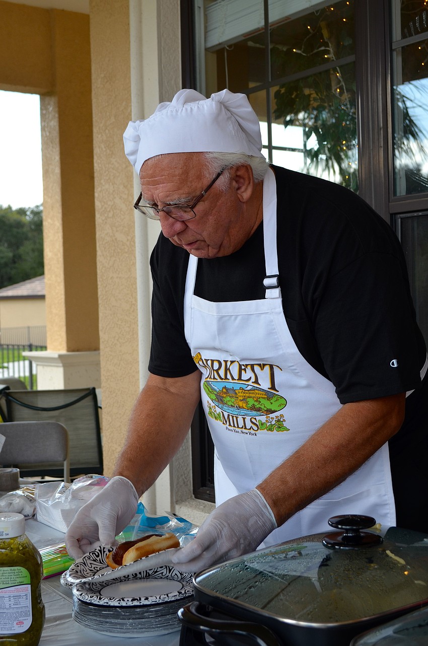 Jim Demakis serves grilled hot dogs to residents.