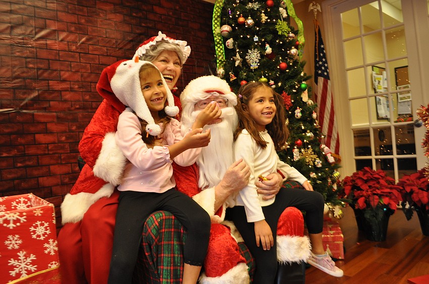 Daniela Landry-Hernandez gives Santa a fake nose with the help of her sister, Alexandra.
