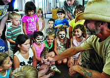 Children gather around Justin Matthews, of Matthews Wildlife Rescue, for a better look at Woody, the screech owl, during an All Godâ€™s Children preschool summer camp.