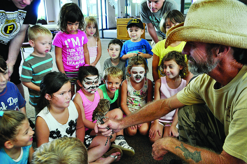 Children gather around Justin Matthews, of Matthews Wildlife Rescue, for a better look at Woody, the screech owl, during an All Godâ€™s Children preschool summer camp.