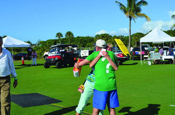 Holly Baran hugs Longboat Key Gourmet Lawn Party Chairman Michael Garey after winning the second prize of "A Year of Delicious Dining" in the event's raffle Dec. 6, at the Longboat Key Club's Islandside driving range.
