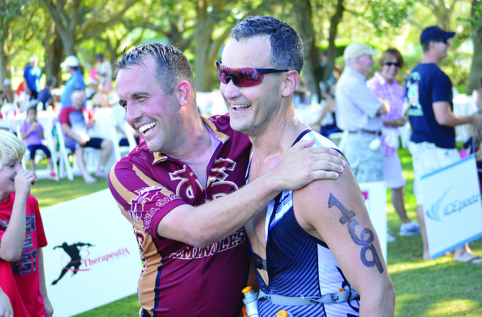 Travis Goulet and Brian Helgemo hug after crossing the finish line at the Oct. 19 Longboat Key Triathlon.