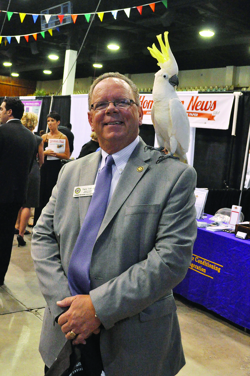 Gary Tibbetts meets Kelly, a sulphur crested cockatoo from Save at Seabirds, at the sixth annual East Meets West regional business expo at Robarts Arena.