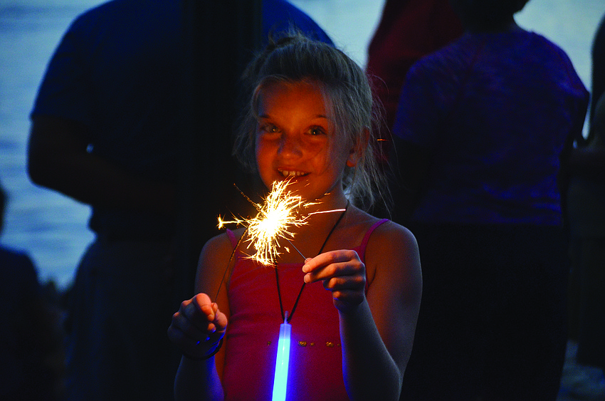 Kayla LeBlanc lights a sparkler at the downtown Fourth of July parade.