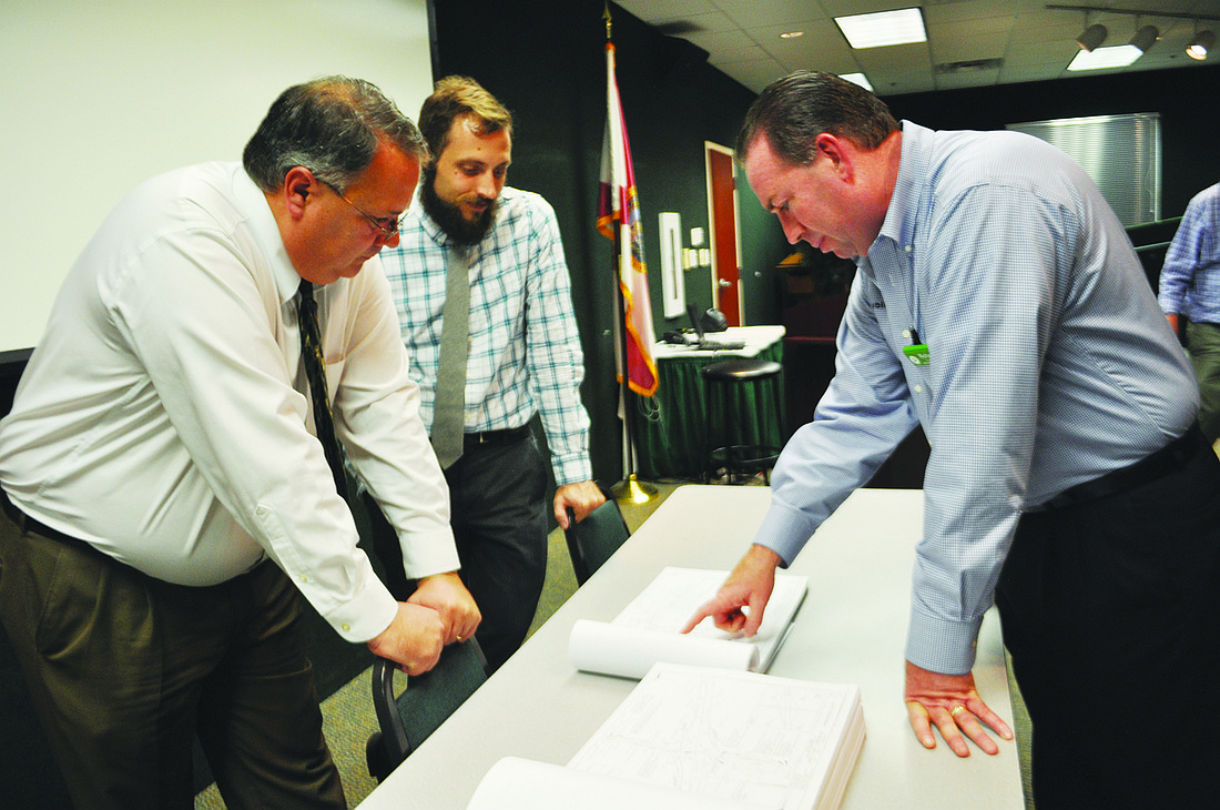 Project consultants Donnie Holcomb, front, and Jason Starr, behind, review construction drawings with Publix Manager Richard Nelson during a December meeting with Market Street merchants. File photo