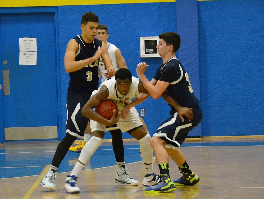Sophomore Brion Whitley fends off Logan Long and Aiden Crume of Southwest Florida Christian Academy.