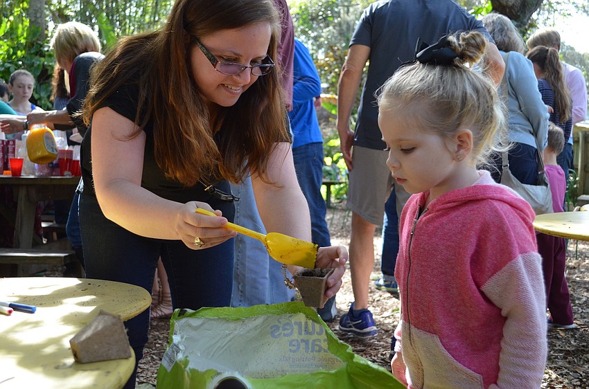 Emily and Alana Duffy fill a pot with soil to plant parsley during the Birthday of the Trees party.