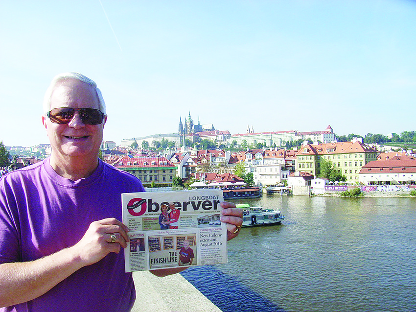 River REPORT. Michael Katz reads his Longboat Observer on the Charles Bridge in Prague. The bridge crosses over the Vltava River and was constructed around 1357.