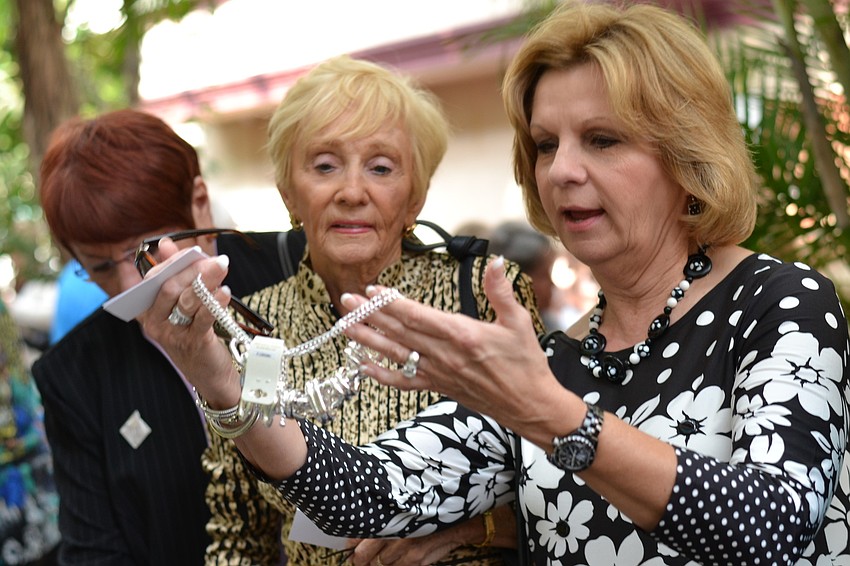 Joan Dickson and Claudia Rovens admire a piece of jewelry on sale at the fashion show.