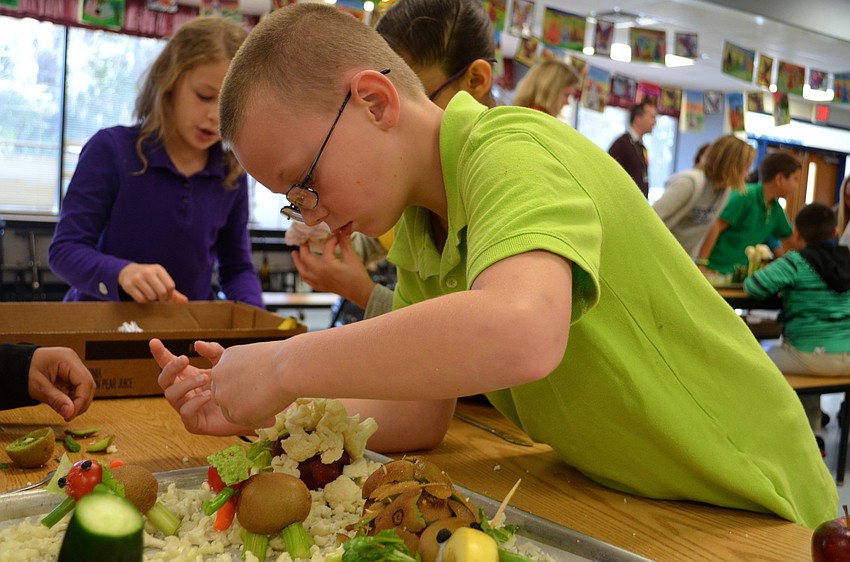 Fourth-grade student, John Collins, crafts an animal out of cauliflower, lettuce and other vegetables.