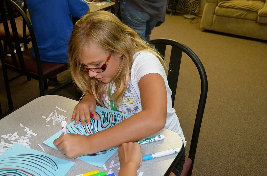 Bella Warmpier focuses on filling in the lines with bright-colored markers.