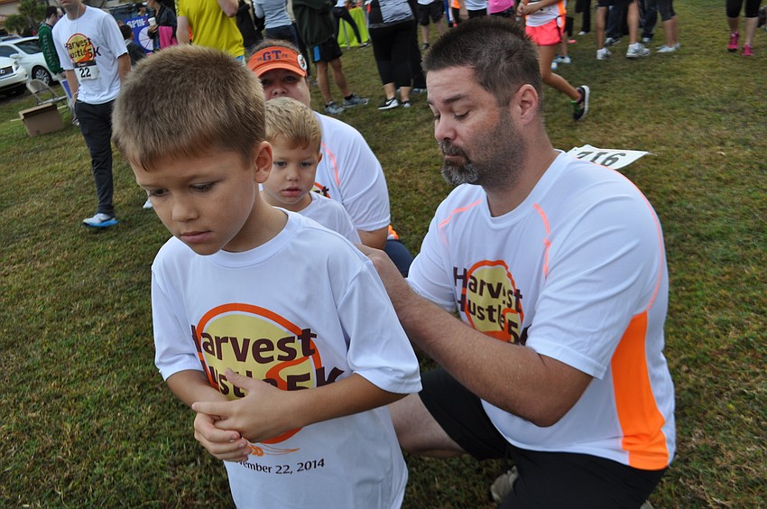 FCCI employee Matt Inman secures a number to the back of his son Aidan, left.