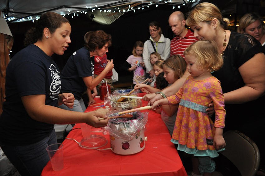 Sami Copeland helps Sienna and Candice Carr decorate a candle.