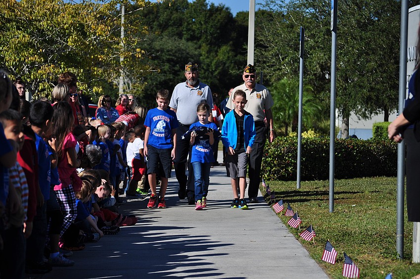 Peyton Coy, Savannah Foil and Caden Salefsky carry the American flag in front of Braden River VFW Post 12055 members Ret. Sgt. Maj. Bill Jackson and Ret. Army Col. Gill Ruderman.