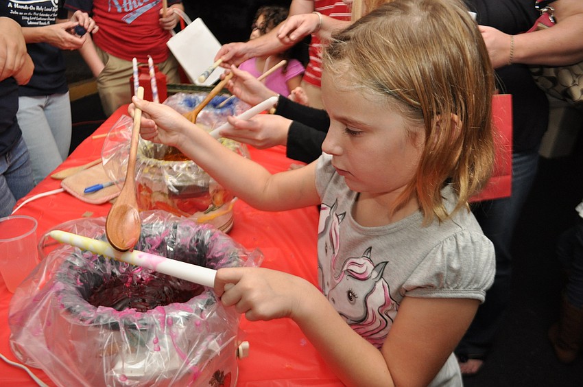 Olivia Carr adds color to a candle.