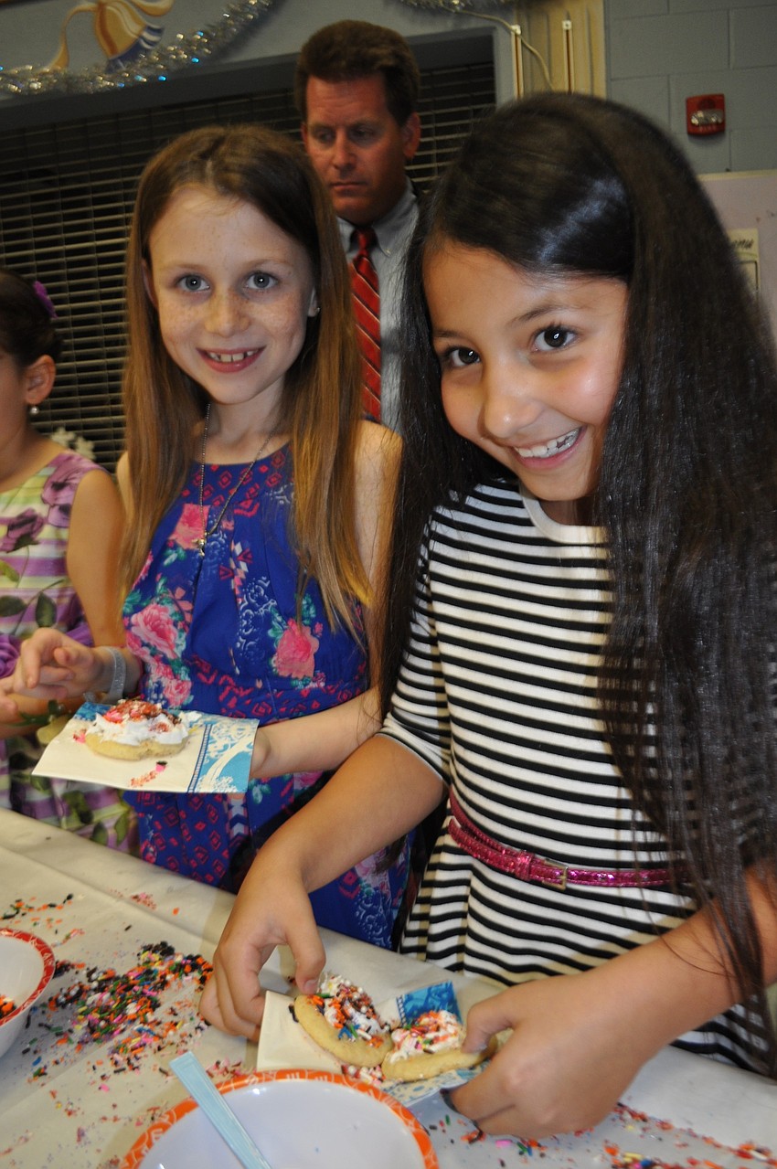 Keira Fonseca, front, and Miley Coffey, behind, mound icing and spindles atop their sugar cookies.