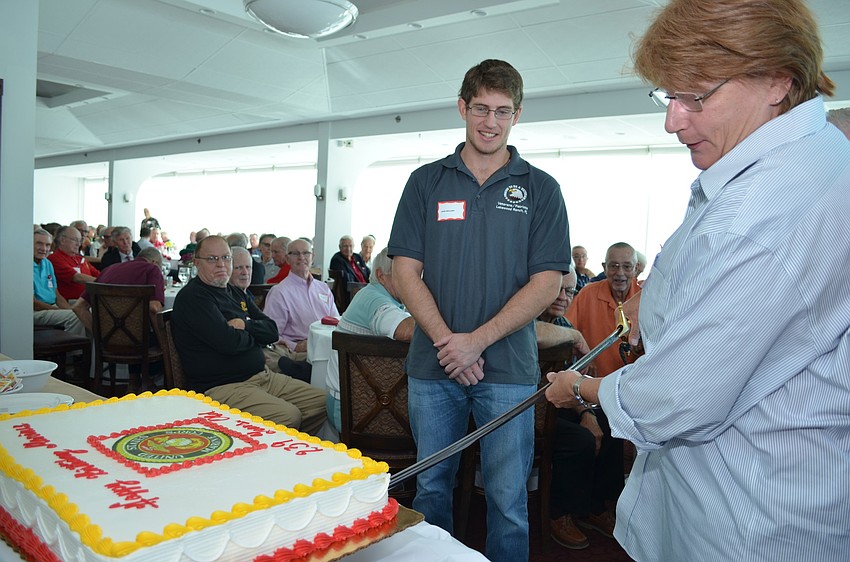 Mary Streppone cuts the birthday cake with a sword to represent mothers of Marines.