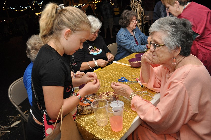 Anja Schwarzbauer receives help making a bracelet from Marie Sankowski.