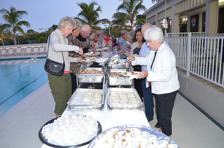Attendees fill their plates with salad, hush puppies, friend and grilled fish, coleslaw and key lime pies.