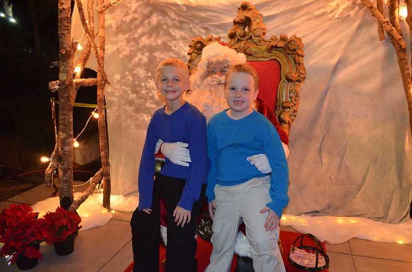 Evan Scott, 8, with brother Ethan, 6, sit on Santaâ€™s lap.