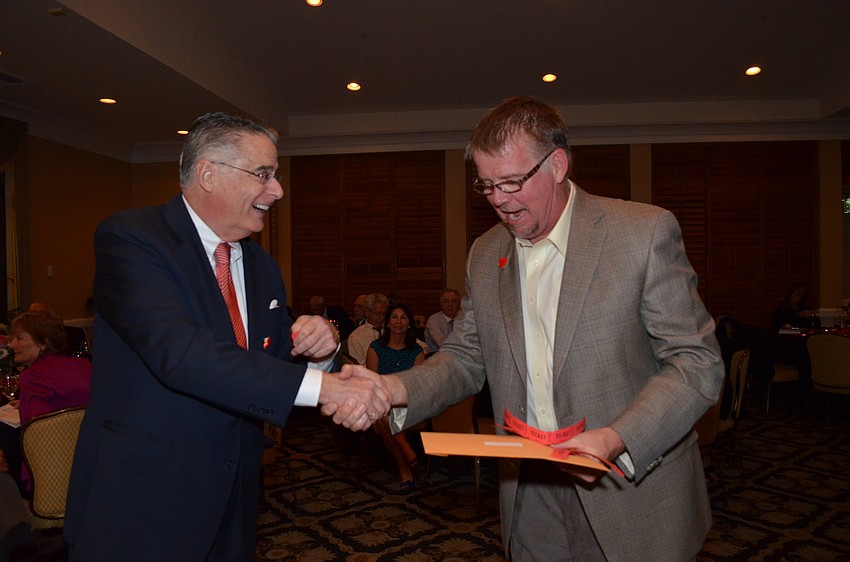 Armando Linde hands Tim Watkins a prize from the raffle that included more than 20 prizes.