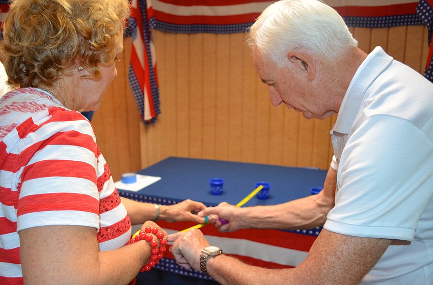 Manny Joaquim instructs Bev Harlfinger at a game booth.