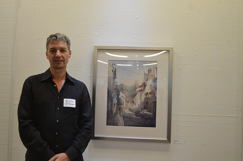Vlad Yeliseyev with his painting, â€œOld Street,â€ a rendering of a street in Amboise, France.