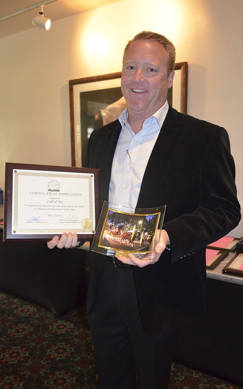 President Scott Macdonald holds his Certificate of Appreciation for Crab & Finâ€™s sponsorship of St. Armands Circle Associationâ€™s Holiday Party.