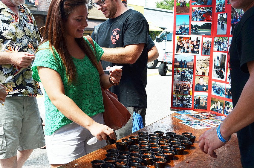 Ariana Steltman picks up a chili-tasting cup from the Fire & Iron booth.