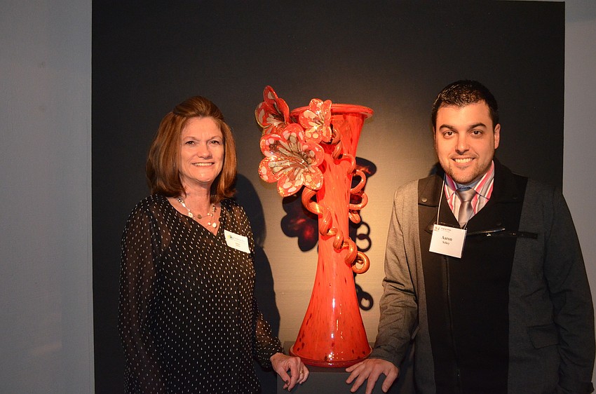 Debbie Clason, office manager of Habatat and Aaron Schey, owner of Habatat in front of â€œRed Vessel with Red Flowersâ€ by Dale Chihuly
