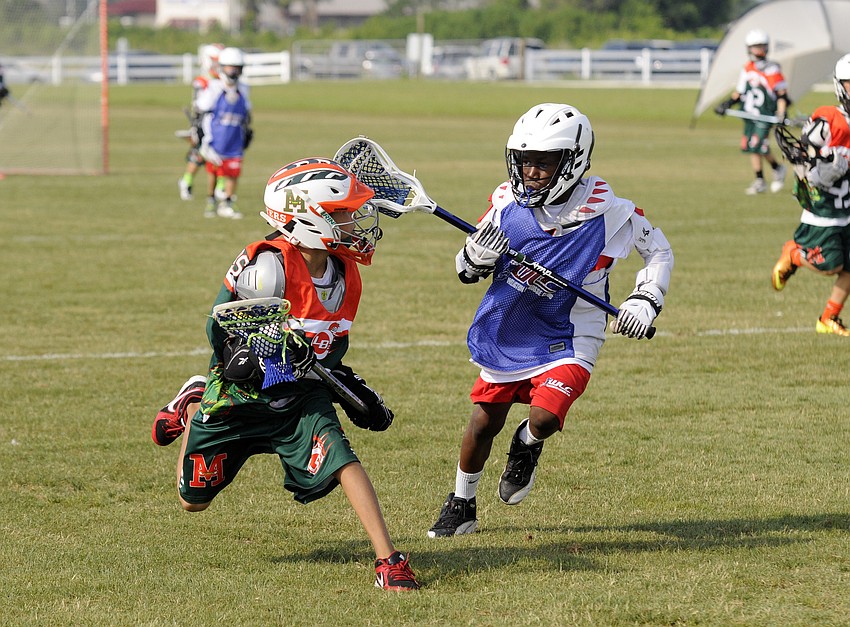 Monsters U9 player Clay Brown looks to maneuver around a Wellington Lacrosse Club defender during their opening game May 24.