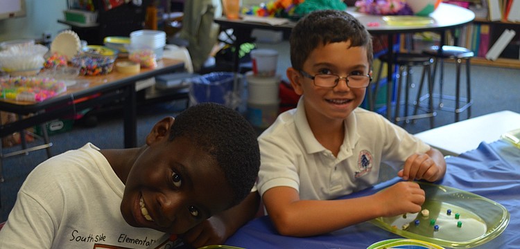 Benjamin Cristogoli and Jacob Todd make bead necklaces.