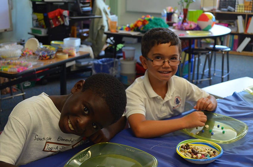 Benjamin Cristogoli and Jacob Todd make bead necklaces.