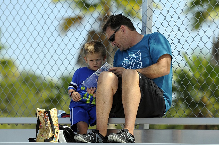 Steve Butler looks over the program with his 3-year-old son Lance. The two planned to attend all five mixed relay events June 8, and were especially looking forward to the laser pistol shooting.