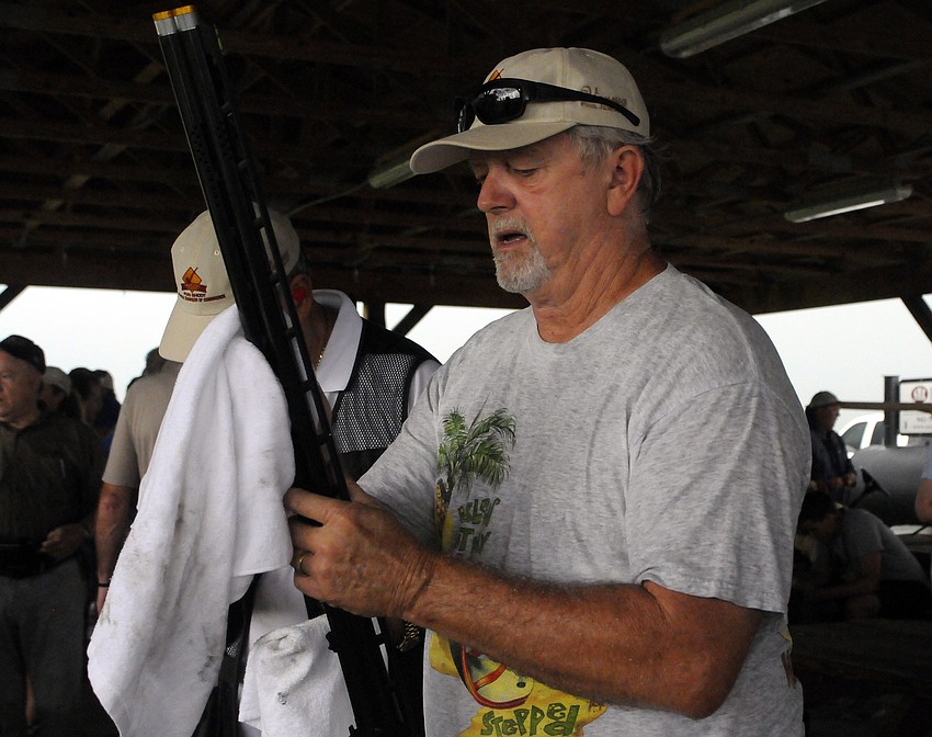 Larry Arnold dries off his gun after thunderstorms prematurely stopped the shoot.