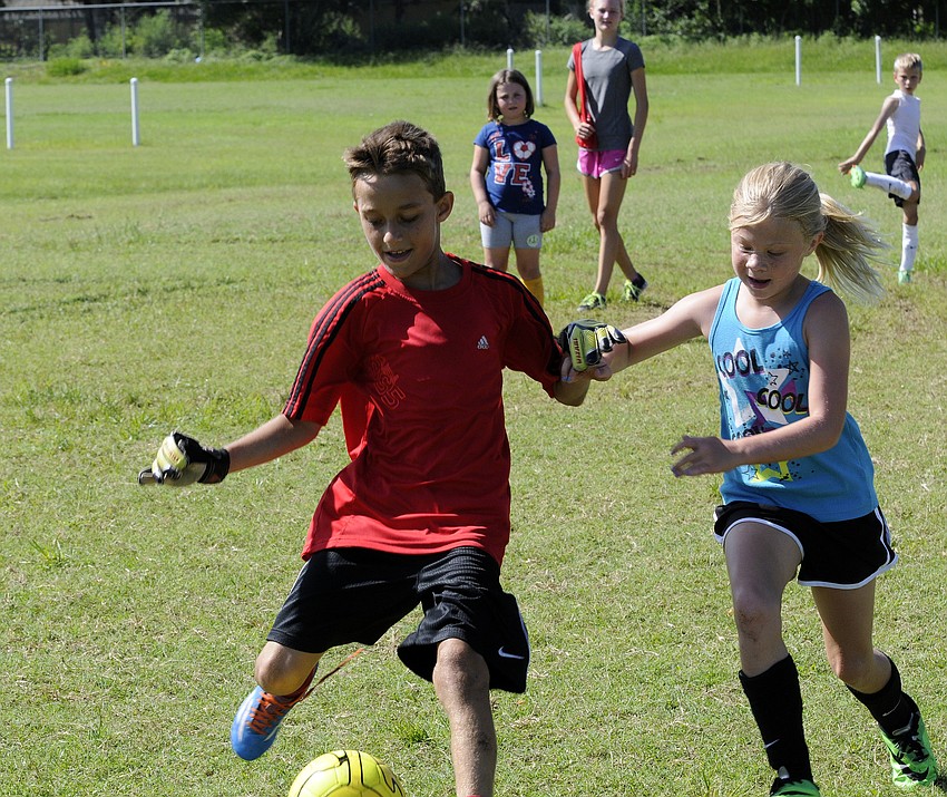 Nine-year-old Josh McManis and 8-year-old Abbey Burwood battle for possession during a scrimmage.