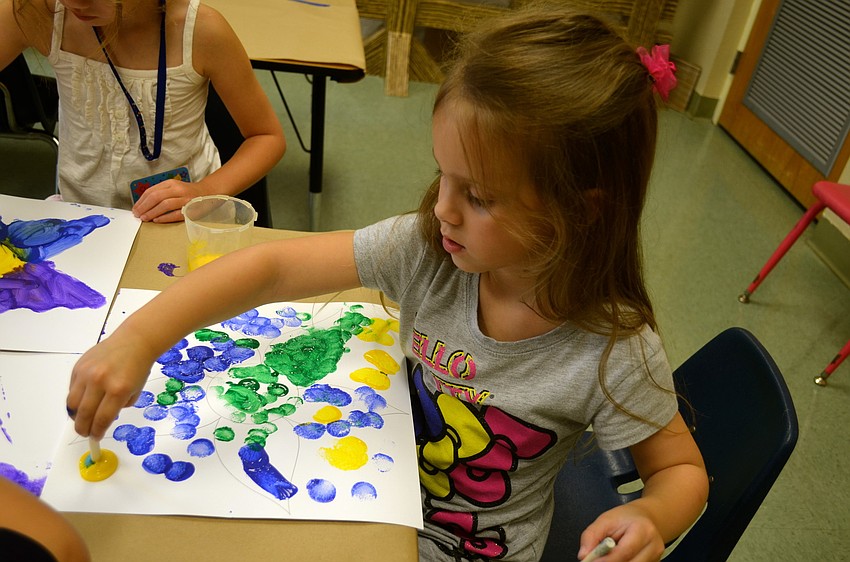 Bellarae Goff paints a drawing of a flower.