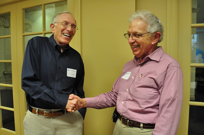 Gary Chase and Herb Schimmel shake hands as they prepare for dinner.